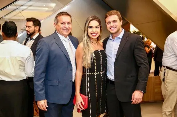 O novo presidente da ABF Rio, Beto Filho (esq.), posa em fila ao lado do filho Sandro Nobre (dir.) e da noiva dele, Naura Guimarães (centro). Os três sorriem olhando na direção da câmera.
